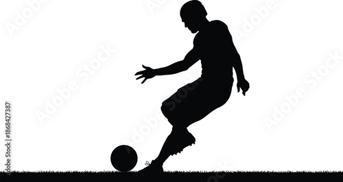 Silhouette of soccer player kicking ball on grass