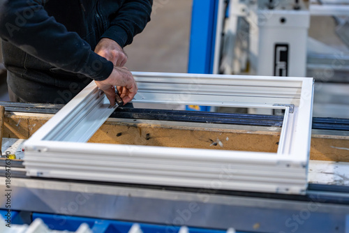 Tableau sur toile Vue de cadres de vitres blancs disposés en atelier, illustrant un environnement de fabrication ou de préparation de menuiseries avec un aspect industriel et organisé