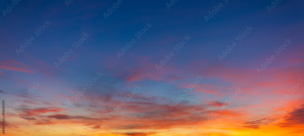 Fototapeta premium Vibrant Panoramic Sunset Sky with Dramatic Pink and Orange Clouds,A breathtaking panoramic view of a sunset sky featuring a vivid transition from deep blue to brilliant orange and pink hues,
