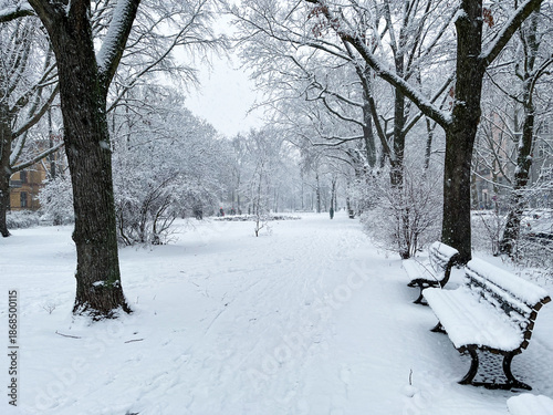 Snow covered park with benches at Grimmstrasse in Berlin Kreuzberg on a winter day in January 