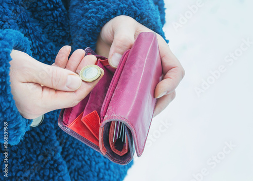 A pink wallet and euro coin in a woman's hands, selective focus.