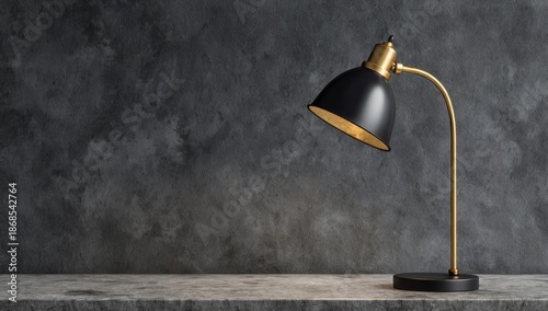 Black and gold desk lamp sitting on a concrete surface against a dark, textured wall