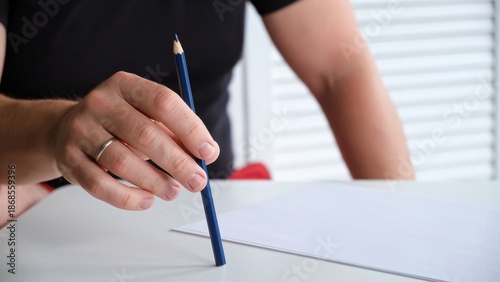 Foto A man tapping a pen on a table with a blank sheet of paper