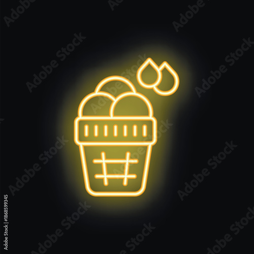 Yellow neon laundry basket filled with clothes and water drops on black brick wall