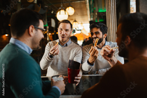 Foto Group of cheerful friends eating salty pretzel sticks and chatting while waiting for their beer order at a bar table in a cozy pub