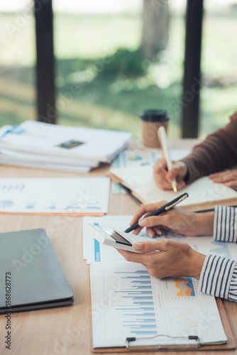Focused Financial Review: Hands diligently engaged in detailed financial analysis. Charts and graphs are meticulously examined in an office setting.