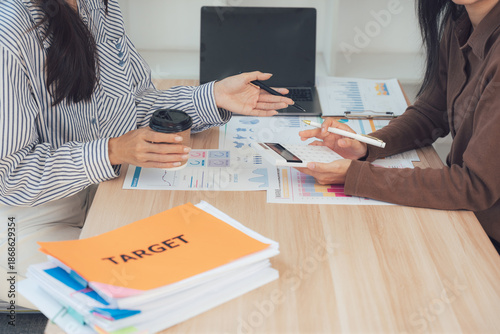 Fotografía Business Partnership: Capturing a pivotal business meeting, two professionals are deeply engrossed in a discussion, documents and devices scattered across the table