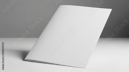 Bright, professional minimalist studio shot of a blank white two-fold brochure mockup leaning vertically on a gray surface.