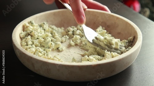 blue cheese and dried cranberries being mixed into a smooth mixture