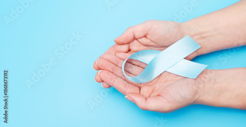 Obraz na płótnie Hands hold a blue ribbon against a blue background