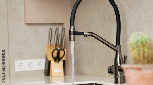 Fotografia Close up of running water from modern kitchen faucet in home interior