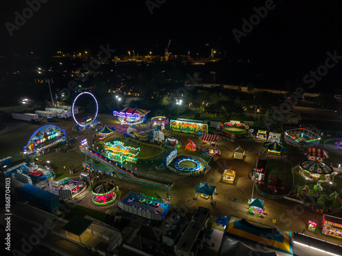 Aerial view of a vibrant carnival illuminated against the night sky, with twinkling lights and thrilling rides creating a mesmerizing scene, Nassau, Bahamas.