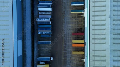 Top down aerial view of semi-trucks and trailers lined up at industrial distribution warehouse, logistics and business transport, cold winter morning Corby, United Kingdom.