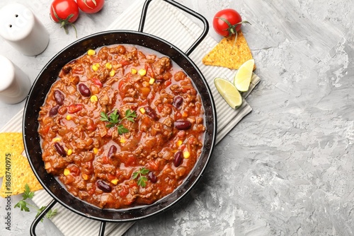 Quadro em tela Delicious chili con carne served on textured grey table, flat lay