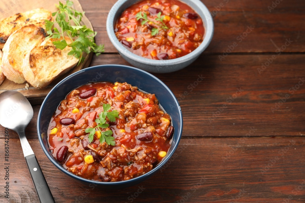 Fototapeta premium Delicious chili con carne served on wooden table, closeup. Space for text