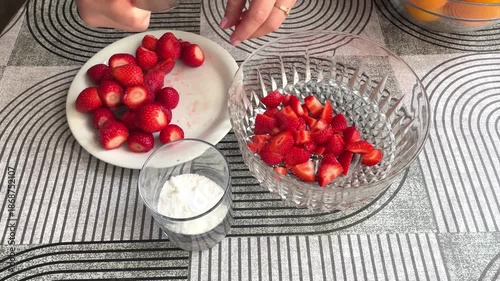 Hands cutting strawberries for dessert. 4K horizontal footage shows female hands slicing fresh strawberries into pieces for sweet recipes and close-up food preparation.
