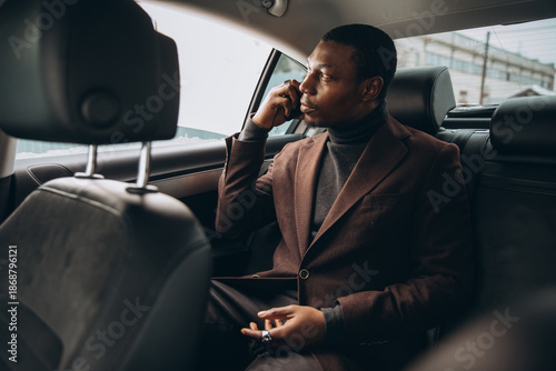 Fotografie Black man conducting business call in car
