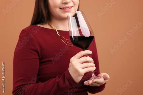 Professional sommelier tasting red wine on pale brown background, closeup
