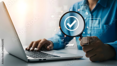 Businessman using laptop with magnifying glass and check mark icon for inspection and verification