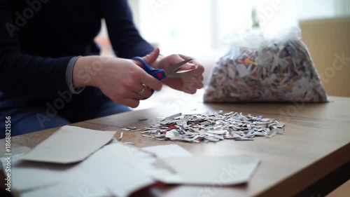 Close-up of female hands cutting paper into small pieces with scissors for recycling