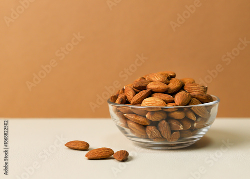 Photos Fresh Raw Almonds in Glass Bowl on Two Tone Background with Copy Space