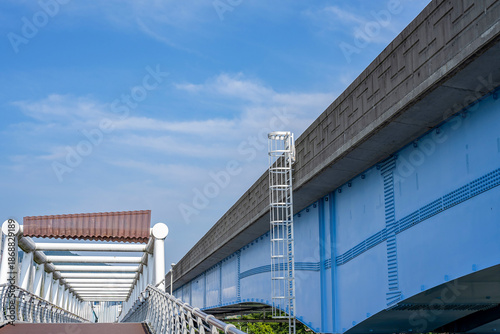 Modern blue steel bridge structure under clear summer sky in Busan