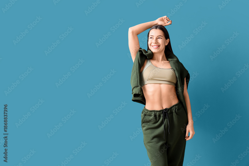 Fototapeta premium Young woman in khaki sports suit on blue background