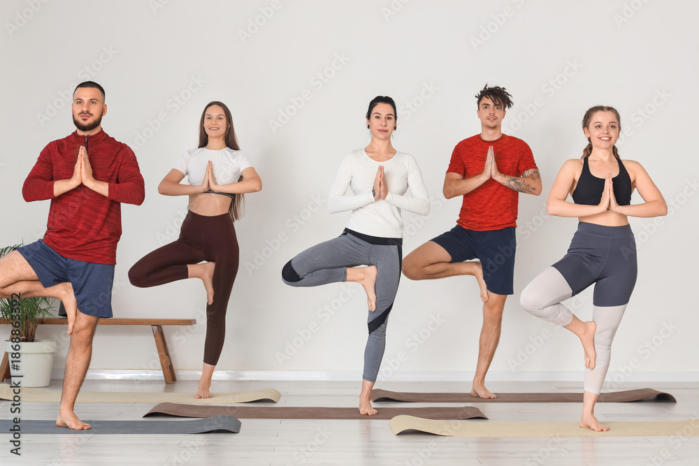 Obraz premium Group of sporty young people doing yoga in gym