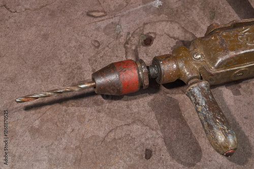 Vintage metal hand drill with wooden elements and visible wear. Traditional manual drilling tool representing craftsmanship, repair work, and historical technology.