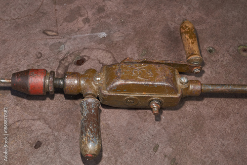 Vintage metal hand drill with wooden elements and visible wear. Traditional manual drilling tool representing craftsmanship, repair work, and historical technology.