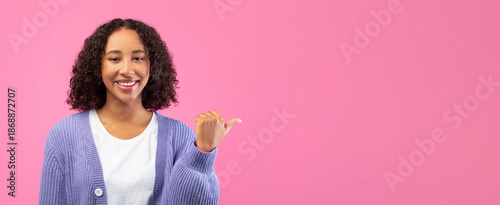 Foto A young woman with curly hair smiles at the viewer while pointing to the side