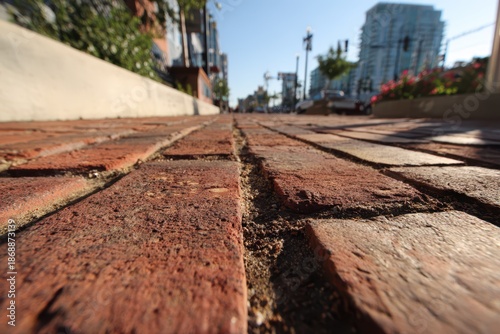 Textured red brick pavement along a quiet urban walkway in sunlight