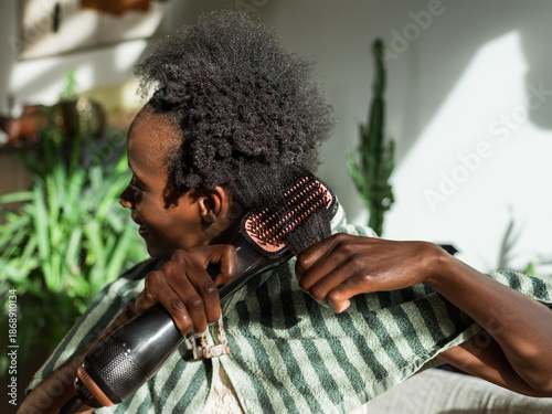 Woman using electric hair styler 