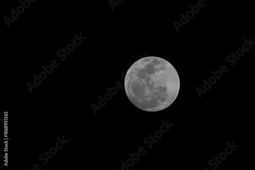 Close-up telephoto shot of a bright Full Moon isolated against a pitch-black sky. The image reveals sharp details of the lunar surface and craters, with ample space for text.