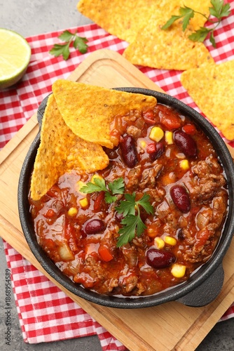 Delicious chili con carne served with nachos and lime on grey table, flat lay © New Africa
