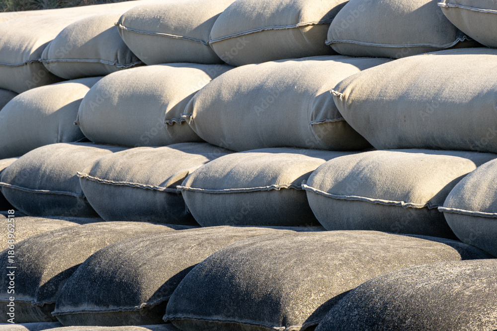 Obraz premium Stacked sandbags used for erosion control and flood mitigation along a developed shoreline or infrastructure edge in Australia. Protective engineering for environmental protection