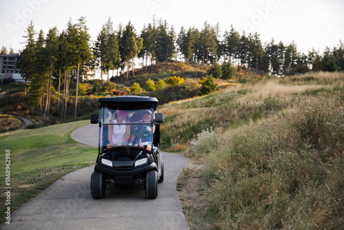 Candid family ride in a golf cart on a scenic park path
