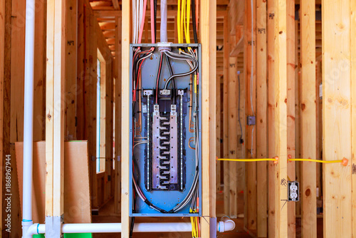 Workers have installed an electrical panel in beams framework of house being built at residential neighborhood.