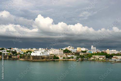Epic waterfront view of Puerto Rico skyline beneath heavy dark clouds, foreground water