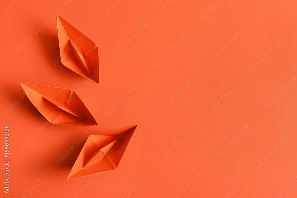 Naklejka premium Orange paper boats on color background