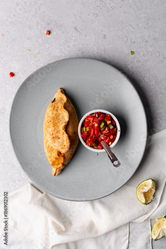 Quadro em tela Overhead view of baked empanadas with pico de gallo on a grey plate, top view of