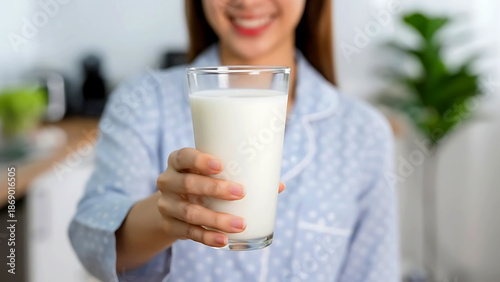 Close-up photo of a woman holding a glass of fresh milk toward the camera. Concept of healthy lifestyle, nutrition, calcium intake, and daily wellness.