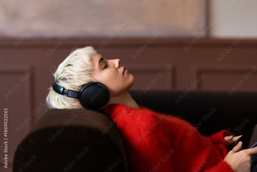 © OchreOchre/Stocksy - Blonde Woman Relaxing On Couch With Headphones Listening To Music