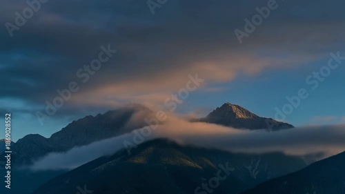 Timelapse of moving clouds over mountain peaks, dynamic lighting from dawn to dusk, cinematic
