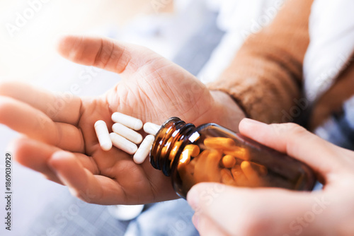 Canvas Print Close up of man hands pouring white capsules from glass bottle into palm