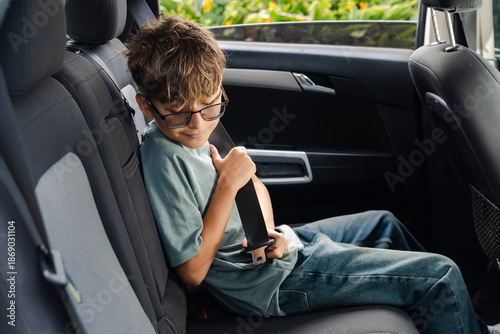 Child fastening seatbelt in car with modern interior and garden view