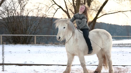 Winter arena scene showing a white Icelandic gelding calmly standing up from the ground on cue while his owner sits bareback