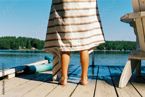 Child's feet on the dock by the lake with towel