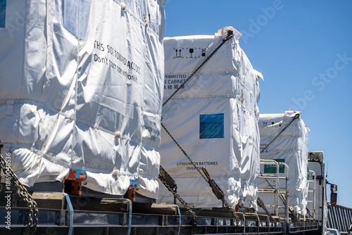 Quadro su tela Large industrial cargo units containing lithium battery systems secured on a flatbed truck for transportation