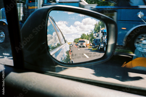 Highway emergency scene reflected in car's rear-view mirror